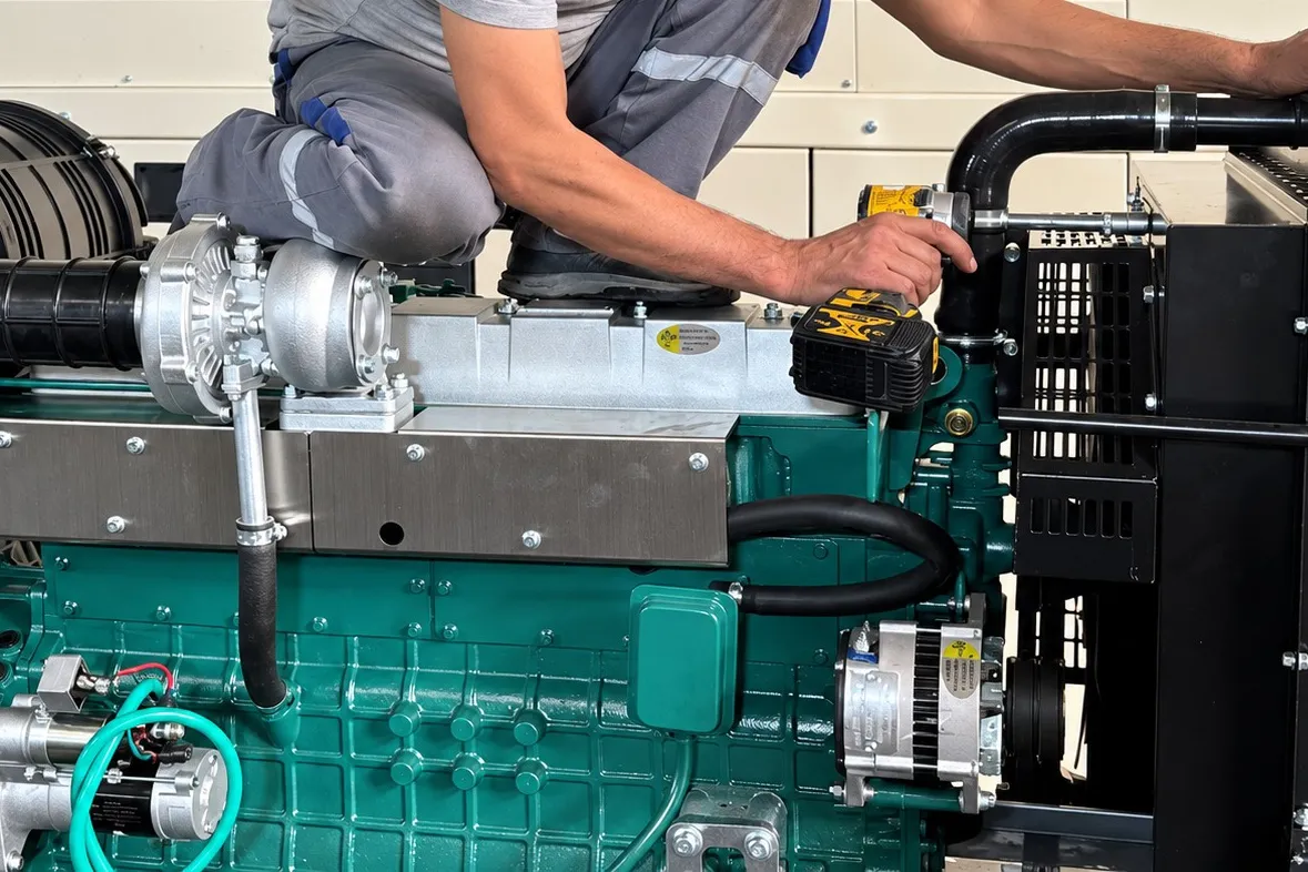 Teknisyen, şase üzerindeki yeşil dizel motorda montaj yapıyor; yakın plan.