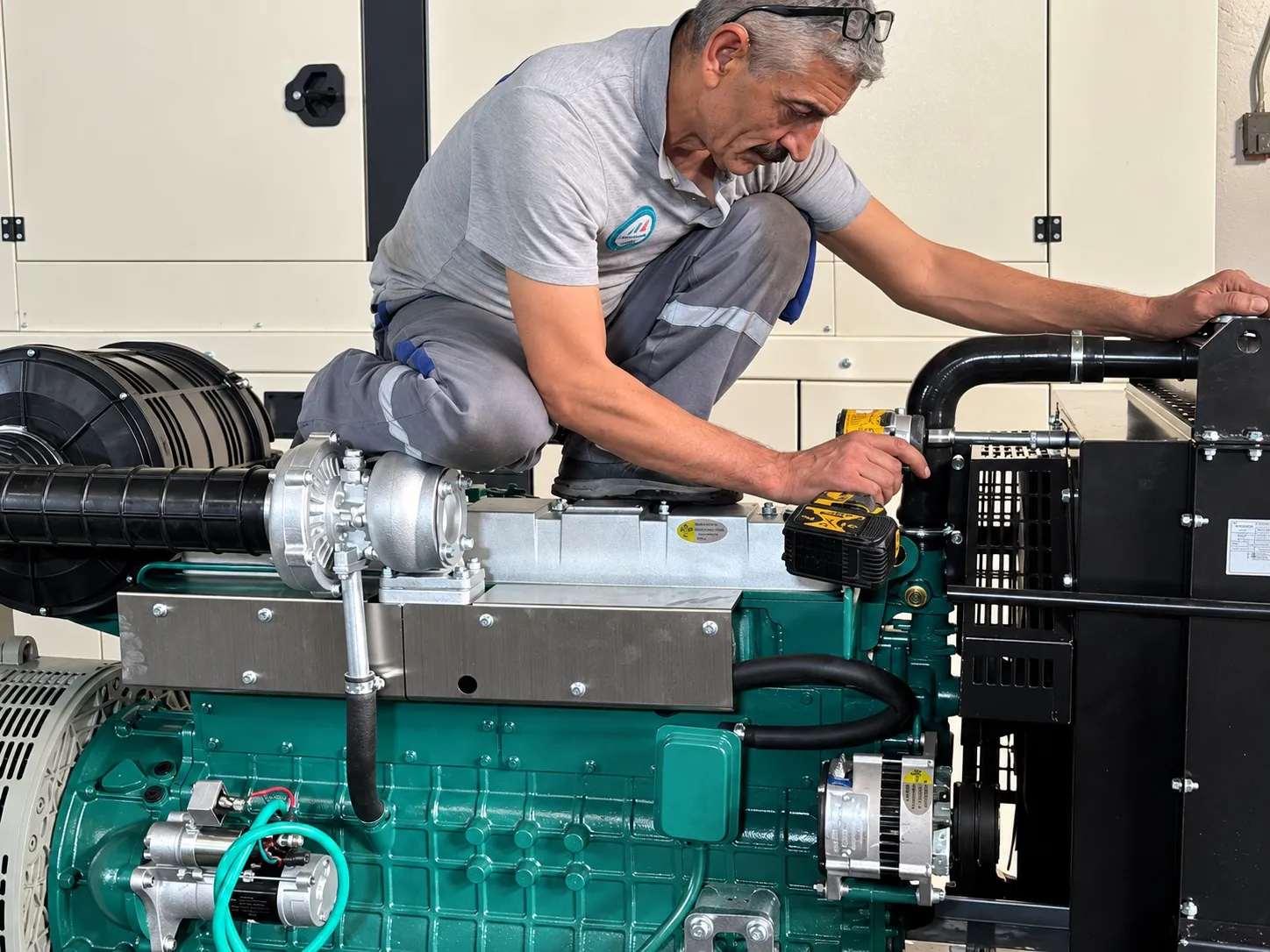 Teknisyen, şase üzerindeki yeşil dizel motorda montaj yapıyor; yakın plan.